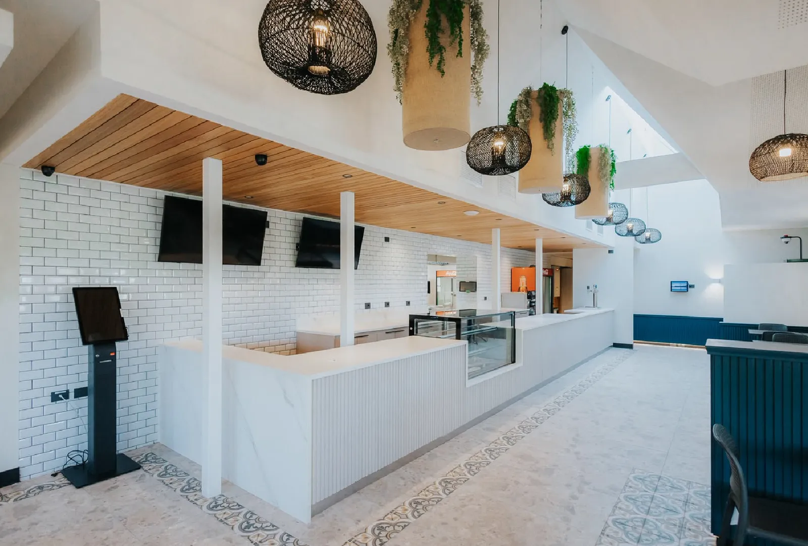 Cafetería con barra blanca y lámparas colgantes, proyecto de MK Arq