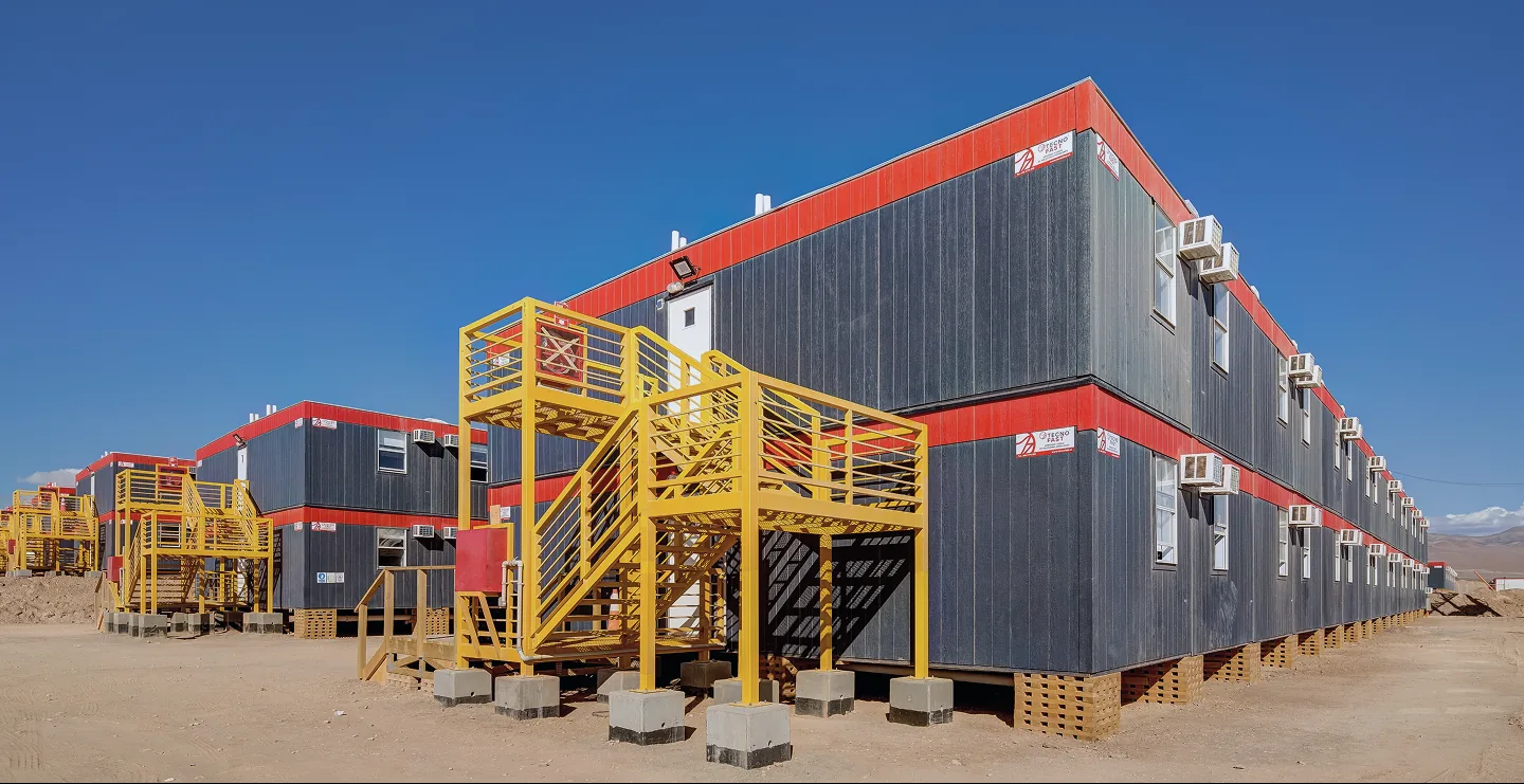 Campamento modular de dos pisos con escaleras amarillas en el desierto